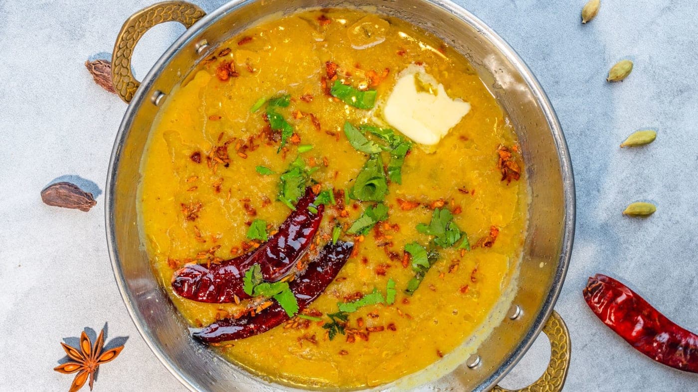 Dal tadka in a brass pan, finished with a tempering of dried chillies and coriander
