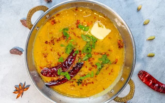Dal tadka in a brass pan, finished with a tempering of dried chillies and coriander